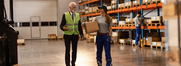 News update banner featuring a warehouse employee in blue coveralls and a supervisor with a safety vest conversing on the warehouse floor, with shelves of boxed inventory in the background. Celebrating 36 years.