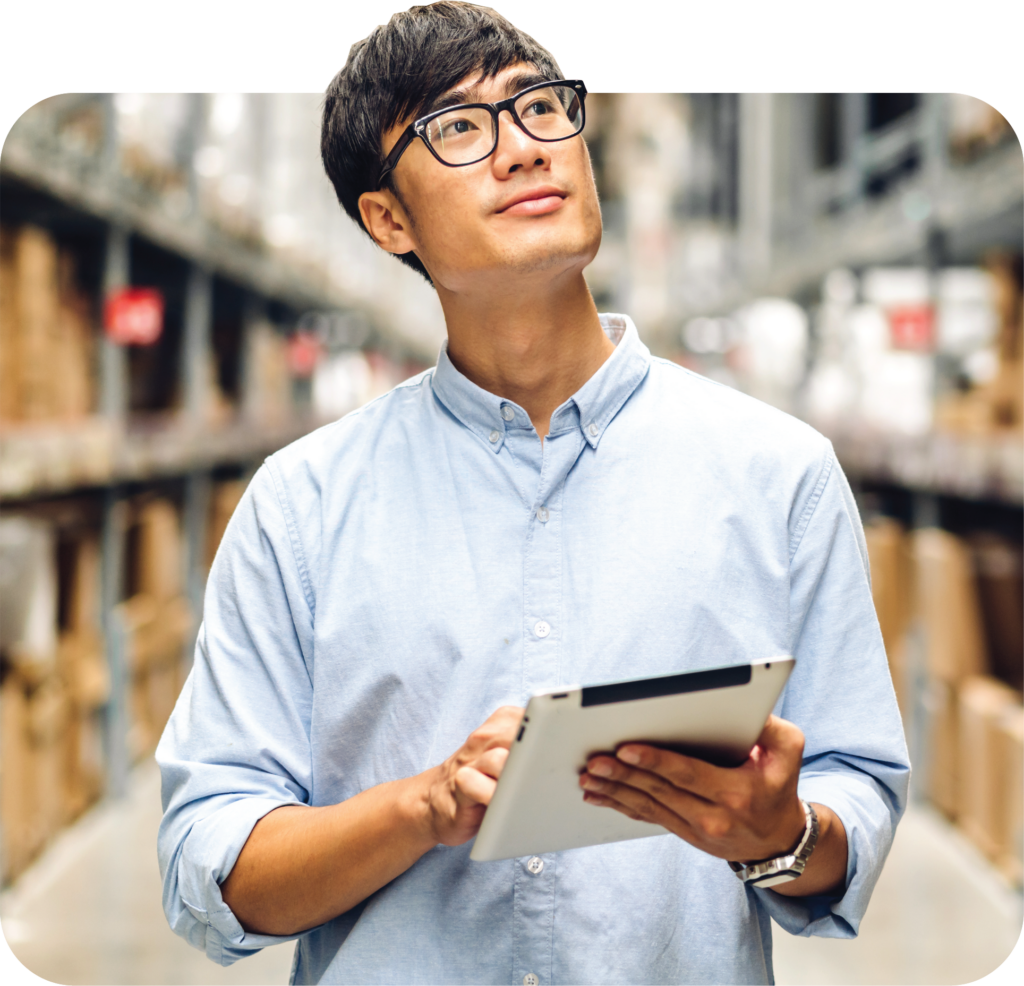 Warehouse employee with glasses holding a digital tablet while thoughtfully looking up, with warehouse shelves in the background and the PPFD branding in the corner.